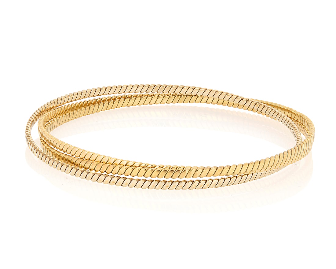 An 18K Tri-Color Gold Bangle: An 18K Tri-Color Gold Bangle Of an interlocking design featuring yellow, rose and white gold Inner circumference: 7 3/4 in. 21.8 grams gross