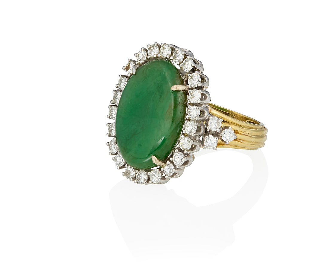 An 18K Bi-Color Gold, Jadeite Jade and Diamond Ring: An 18K Bi-Color Gold, Jadeite Jade and Diamond Ring Centering an oval jadeite jade cabochon weighing approximately 6.89 carats, encircled by round diamonds weighing approximately 1.15 carats Size: 6 1