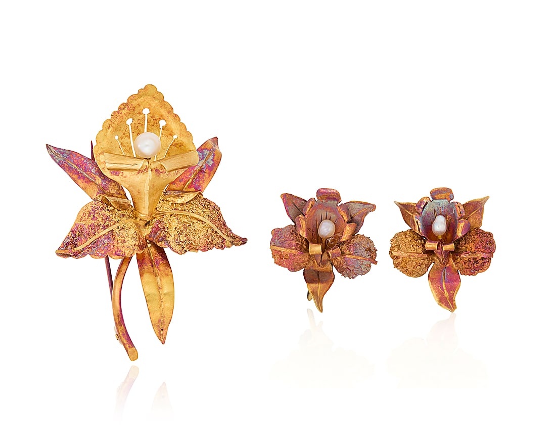 An 18K Gold and Pearl Brooch and Earring Set: An 18K Gold and Pearl Brooch and Earring Set Of an orchid design centering seed pearls 3 pieces Brooch: 2 1/4 x 1 3/4 in., Earrings: 3/4 in. 16.7 grams gross This lot is being offered with no reserve