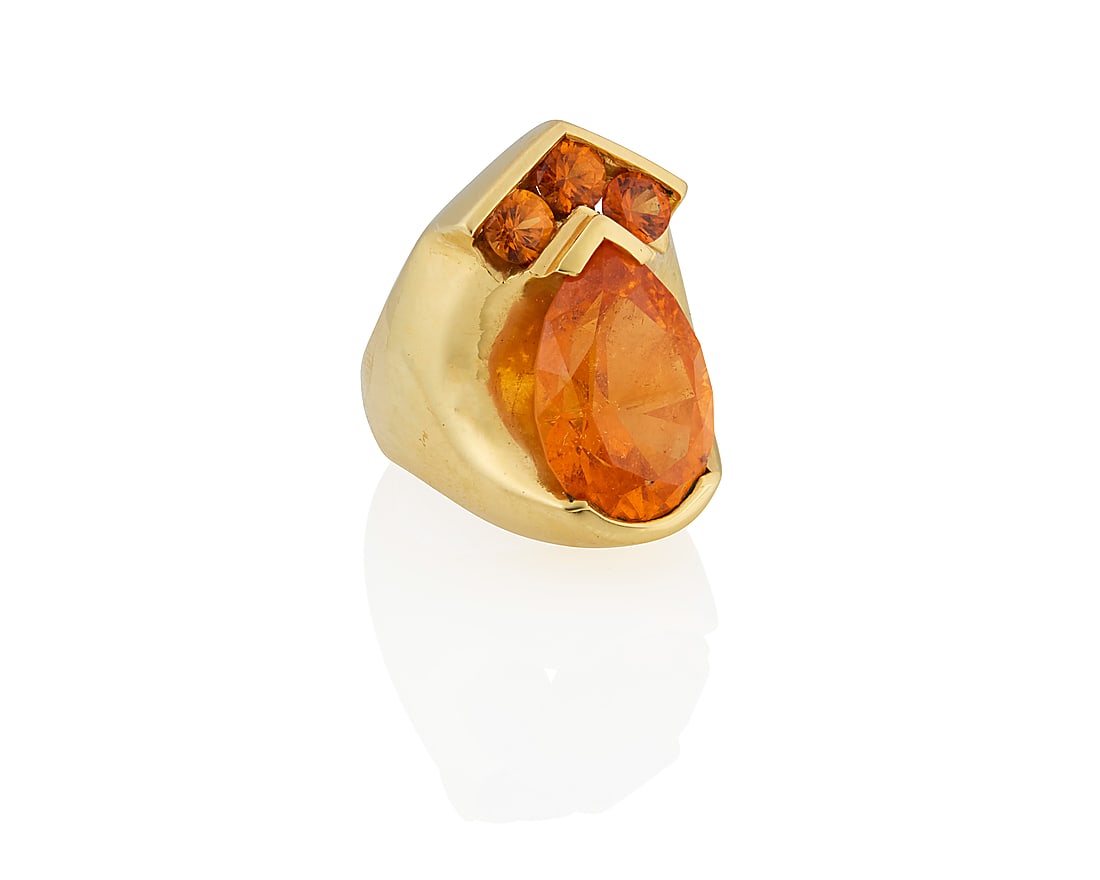 An 18K Gold and Mandarin Garnet Ring: An 18K Gold and Mandarin Garnet Ring Centering a pear-shaped mandarin garnet weighing approximately 17.60 carats, accented by three round mandarin garnets Size: 7 3/4 21.3 grams gross