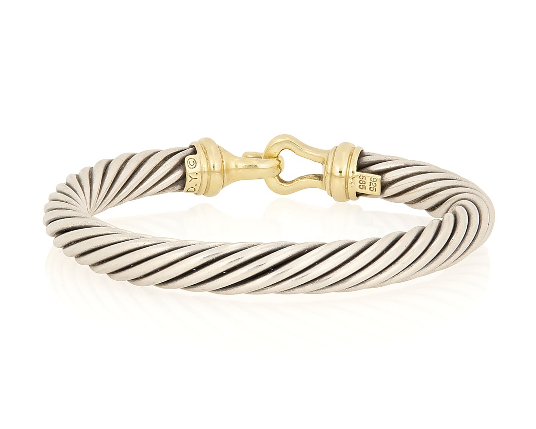 David Yurman: A 14K Gold and Silver Cable Cuff: David Yurman: A 14K Gold and Silver Cable Cuff Featuring a sterling cable design finished with a 14k gold hook clasp, signed D.Y. Inner circumference: 6 1/4 in. 43.7 grams gross This lot is being offe