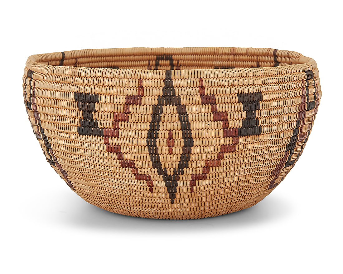 A Washoe polychrome degikup basket: A Washoe polychrome degikup basket Early 20th century; Great Basin The coiled basket with alternating diamond and geometric elements and floating hourglass motifs 4" H x 8" Dia. Provenance: The Robert