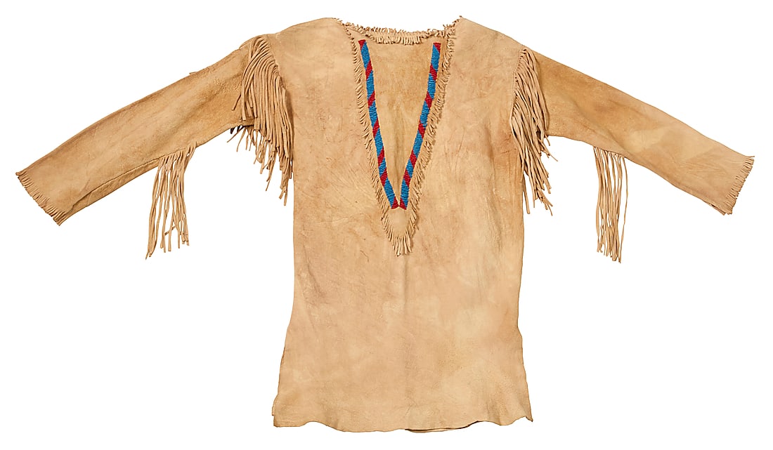 A Plains style child's beaded buckskin shirt: A Plains style child's beaded buckskin shirt Mid-20th century The small long-sleeve shirt with two bands of beaded elements in a V at front, and fringe to shoulders and sleeves 24" H x 14.5" W (across