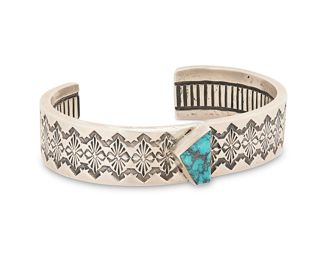 A Southwest sterling silver and turquoise cuff bracelet: A Southwest sterling silver and turquoise cuff bracelet Late 20th/21st century Unmarked A chunky sterling silver cuff with a stampwork band and asymmetrical set turquoise, with ridged banding to inter