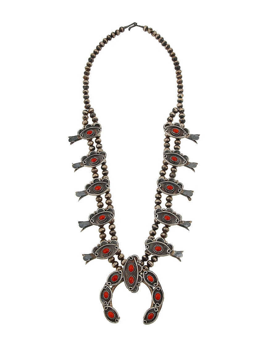 A Southwest sterling silver and coral squash blossom necklace: A Southwest sterling silver and coral squash blossom necklace Mid-20th century Unmarked A double strand necklace with ten blossoms each with a set coral cabochon, suspending a matching naja with set c