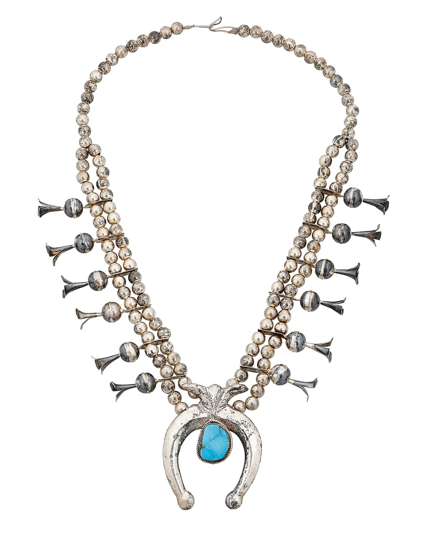 A Southwest silver and turquoise squash blossom necklace: A Southwest silver and turquoise squash blossom necklace Early 20th century Unmarked A double strand of silver beads with twelve blossoms suspending a large cast sterling silver naja, with a later-add
