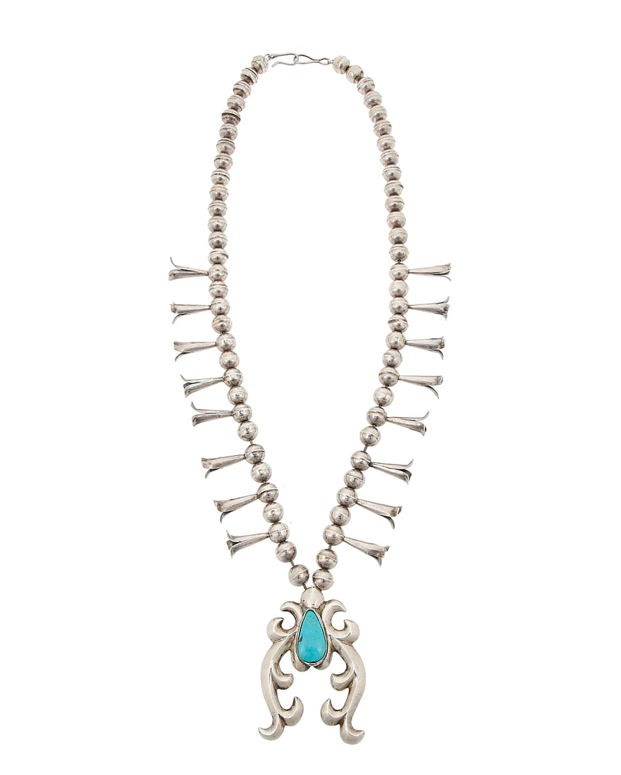 A Southwest silver and turquoise squash blossom necklace: A Southwest silver and turquoise squash blossom necklace Late 20th century Etched: BBB A single strand of silver beads with sixteen blossoms, suspending a sandcast silver stylized naja with a set tear