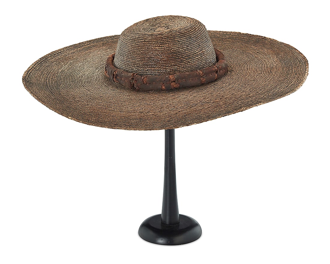 An early Mexican sombrero: An early Mexican sombrero Circa 1860 The pale brown-toned wide brimmed round hat with a low tapered flat crown, likely woven of palm straw, with an added double plaited leather corded band covered wit
