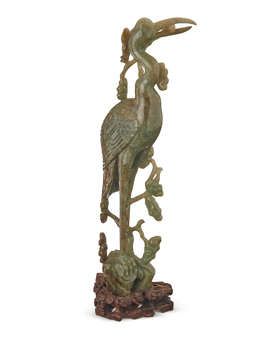 A Chinese jade carving of a Manchurian crane: A Chinese jade carving of a Manchurian crane 20th century Raised on a carved hardwood stand Figure: 10.25" H x 3.625" W x 2.5" D; Overall: 11" H