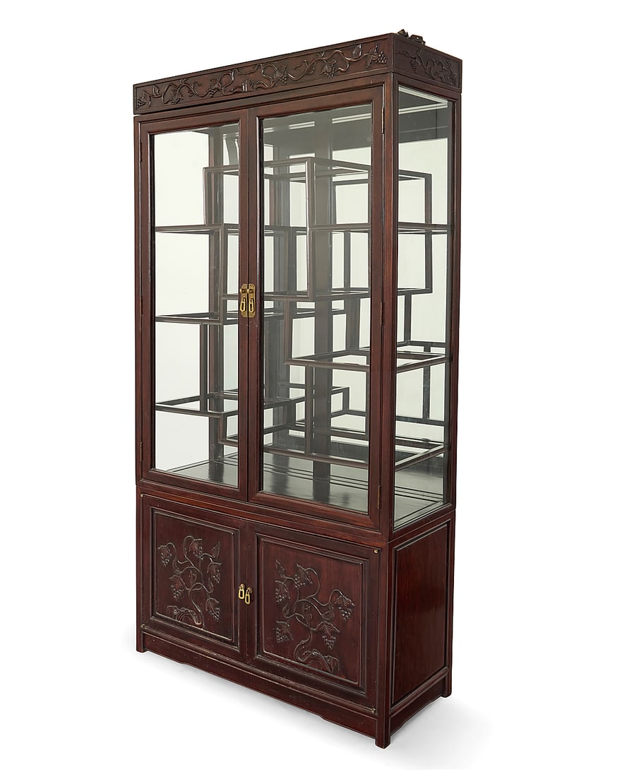 A Chinese carved wood display cabinet: A Chinese carved wood display cabinet 20th century The glazed cabinet above a lower console, the doors carved with grapevine motifs, opening to reveal a single shelf 2 pieces Overall: 78" H x 40.5" W