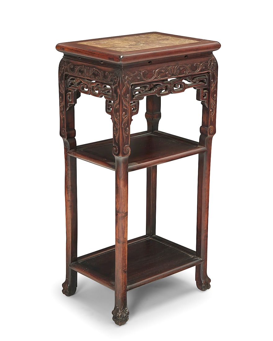 A Chinese carved hardwood table: A Chinese carved hardwood table Mid-20th century With inset marble top above a carved and openwork apron and two undertiers, raised on ball and claw feet 34" H x 16.5" W x 12" D