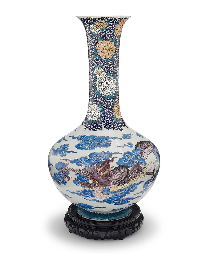 An East Asian polychrome porcelain vase 20th century The stick-neck enameled vase depicting floral: An East Asian polychrome porcelain vase 20th century The stick-neck enameled vase depicting floral motifs to neck above a dragon within clouds to the body, raised on a carved wood stand Vase: 18.75" H