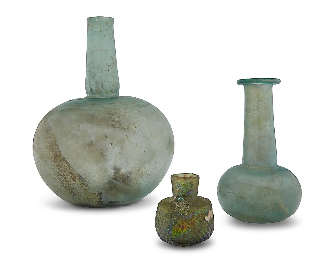 Three Roman iridescent glass vessels: Three Roman iridescent glass vessels 1st century CE 3 pieces Largest: 9.375" H x 6.875" Dia.; Smallest: 2.625" H x 2.25" Dia. Provenance: Loewi-Robertson, Inc. Private collection