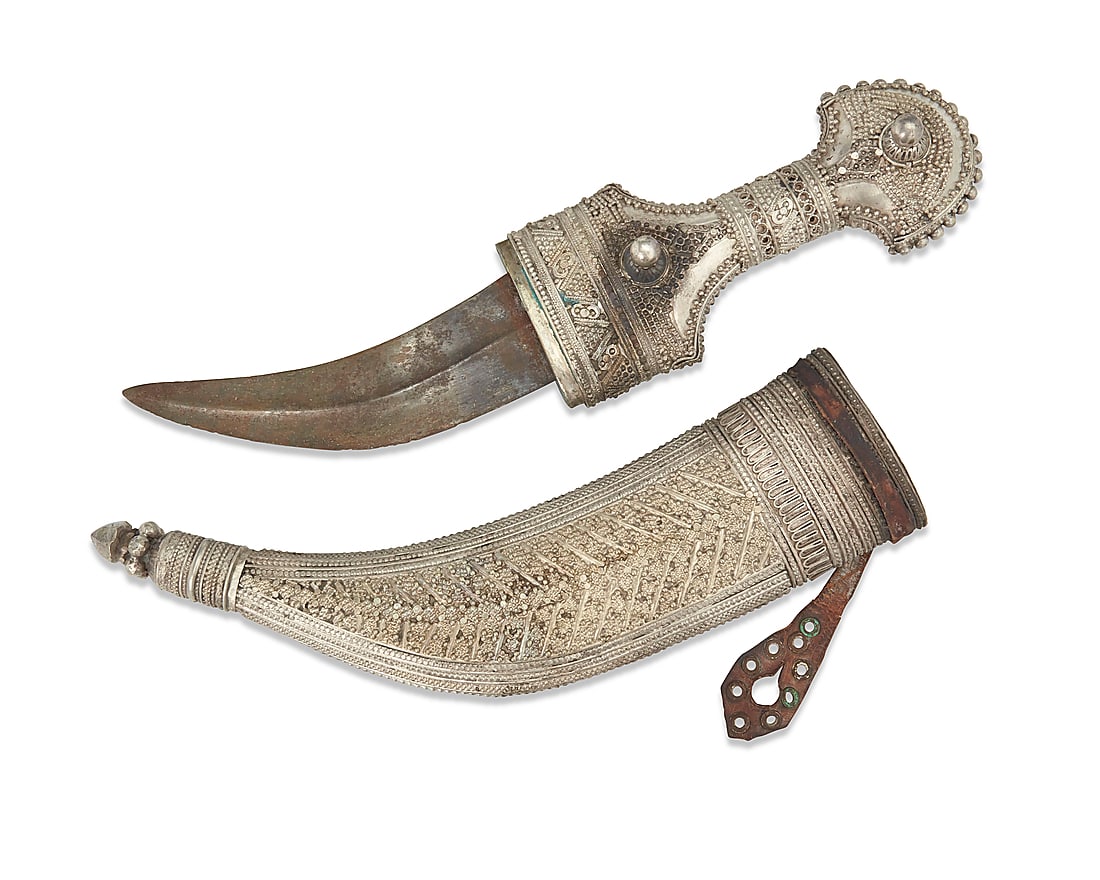 An Arabian silver jambia knife: An Arabian silver jambia knife 19th century With script etched into the pommel; XRF tested for .800 silver Curved steel blade, the sheath with leather strapping Blade: 6.375" L; Hilt: 7.5" H x 3.25"
