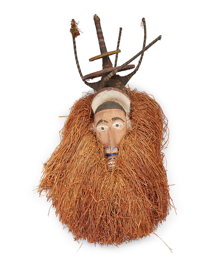 A Yaka Ndeemba polychrome mask: A Yaka Ndeemba polychrome mask Late 19th/early 20th century; Democratic Republic of the Congo The painted carved wood mask with applied raffia, surmounted by a fabric and armature headpiece painted