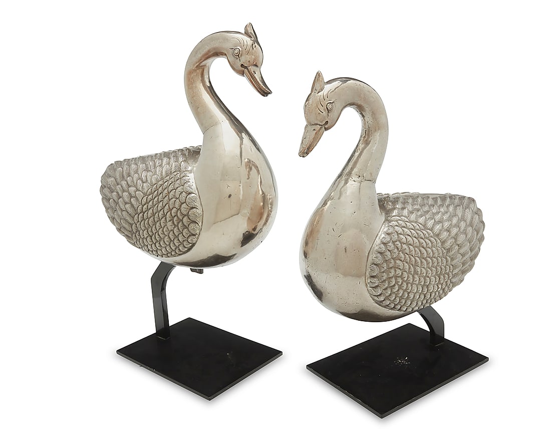 A pair of silvered metal geese: A pair of silvered metal geese 20th century Each weighted silver-plated copper, set on an enameled metal stand 2 pieces Each goose: 15" H x 14" W x 8.5" D approximately; Taller stand: 7.5" H x 10" W