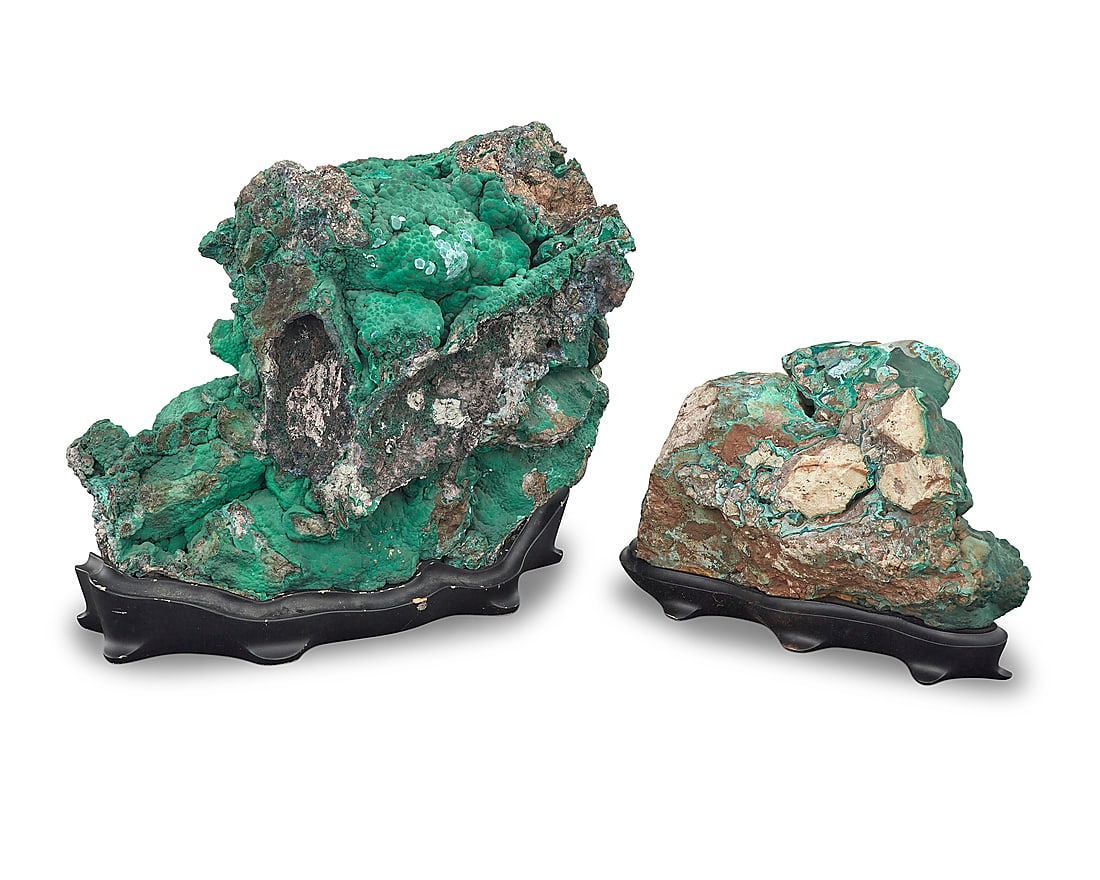 Two malachite specimens: Two malachite specimens Democratic Republic of the Congo The larger with rough overgrowth, each raised on a custom-fitted black stand 2 pieces Overall height or larger 14 3/4 in., width 16 3/4 in.,