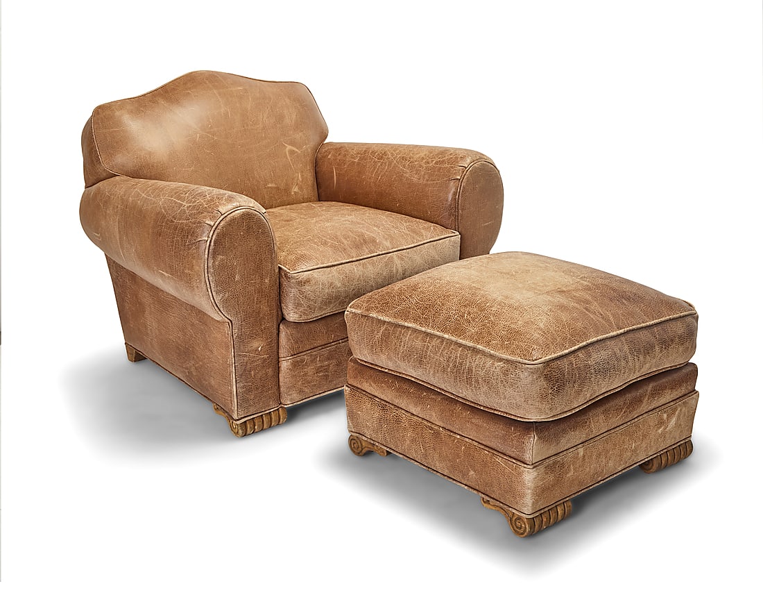 An Art Deco style leather club chair and ottoman: An Art Deco style leather club chair and ottoman Late 20th/early 21st century 2 pieces Height of chair 34 1/4 in., width 44 in., depth 39 in.; ottoman height 19 1/2 in. width 26 1/2 in., depth 26 1/2
