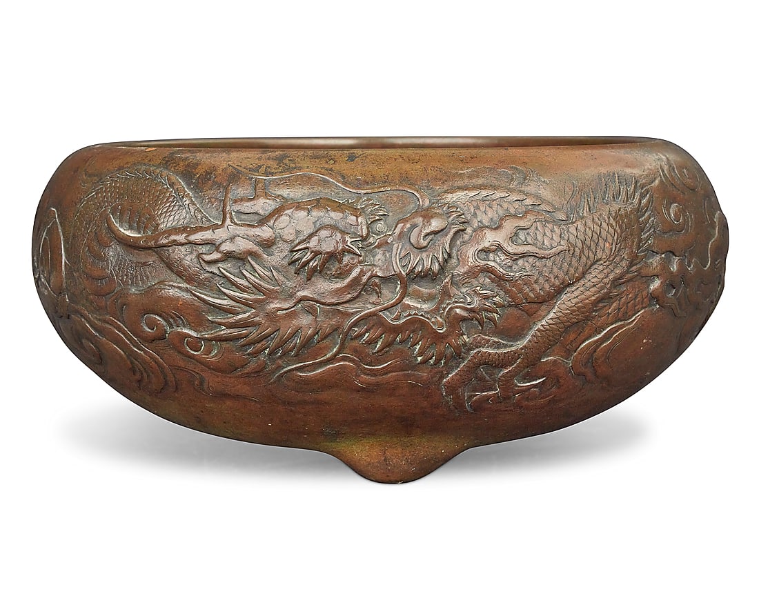 A Chinese bronze jardiniere: A Chinese bronze jardiniere Late Qing dynasty (1644-1912) Unmarked Depicting a dragon in low relief, raised on three protruding feet Height 6 in., diameter 14 in.