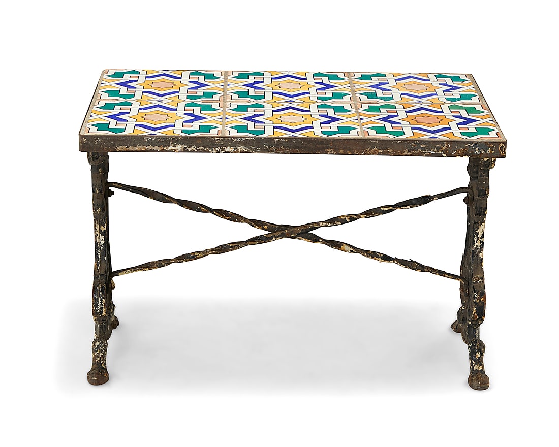 A tile top cast iron low table: A tile top cast iron low table 20th century With Moorish/Spanish Revival geometric pattern glazed ceramic tiles raised on a painted iron base with scroll supports Height 17 1/8 in., width 25 1/2 in.,