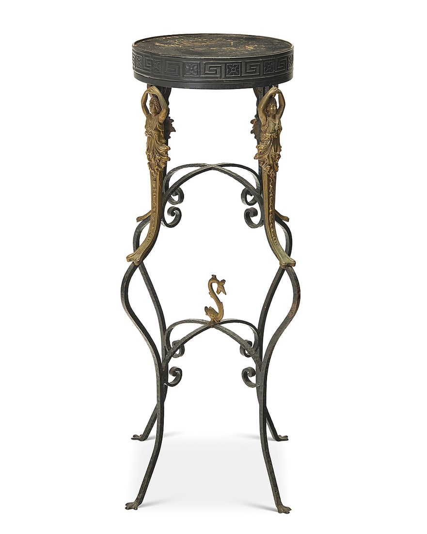 A Neoclassical style wrought iron plant stand: A Neoclassical style wrought iron plant stand Early 20th century The wood top with enameled metal edges decorated with meandering motif, above gold-toned metal mermaids mounted to an enameled wrought