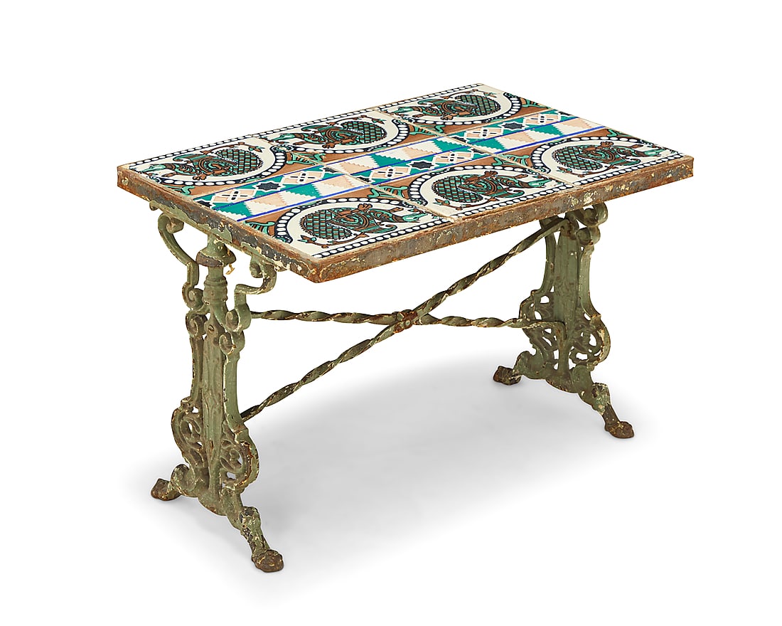 A tile top cast iron low table: A tile top cast iron low table 20th century With Moorish/Spanish Revival figural pattern glazed ceramic tiles raised on a painted iron base with scroll supports Height 17 1/4 in., width 25 1/2 in., de