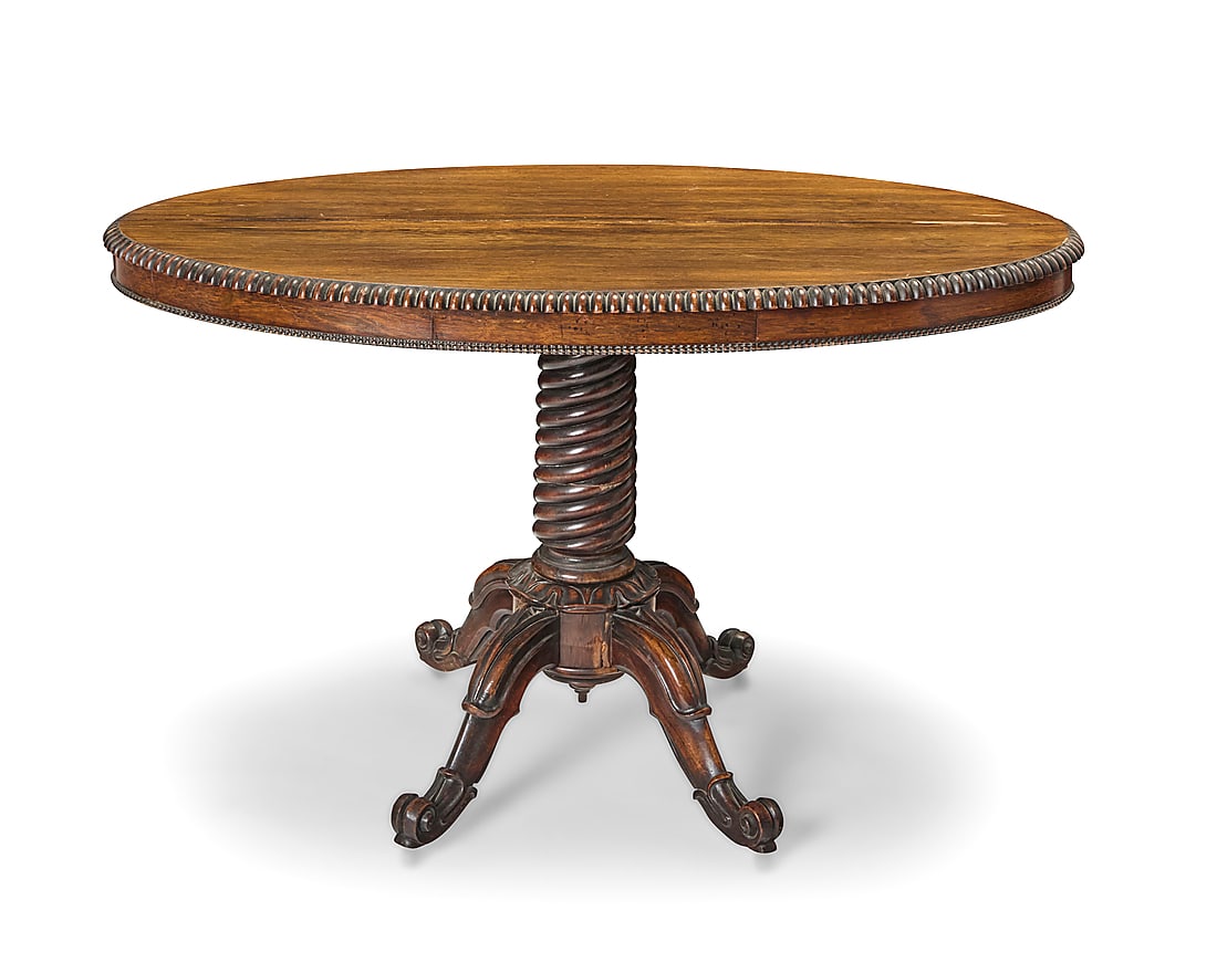 A Victorian rosewood breakfast table: Y A Victorian rosewood breakfast table Late 19th/early 20th century With gadrooned edge and single drawer, raised on a turned support column with four scrolling legs terminating in casters Height 29