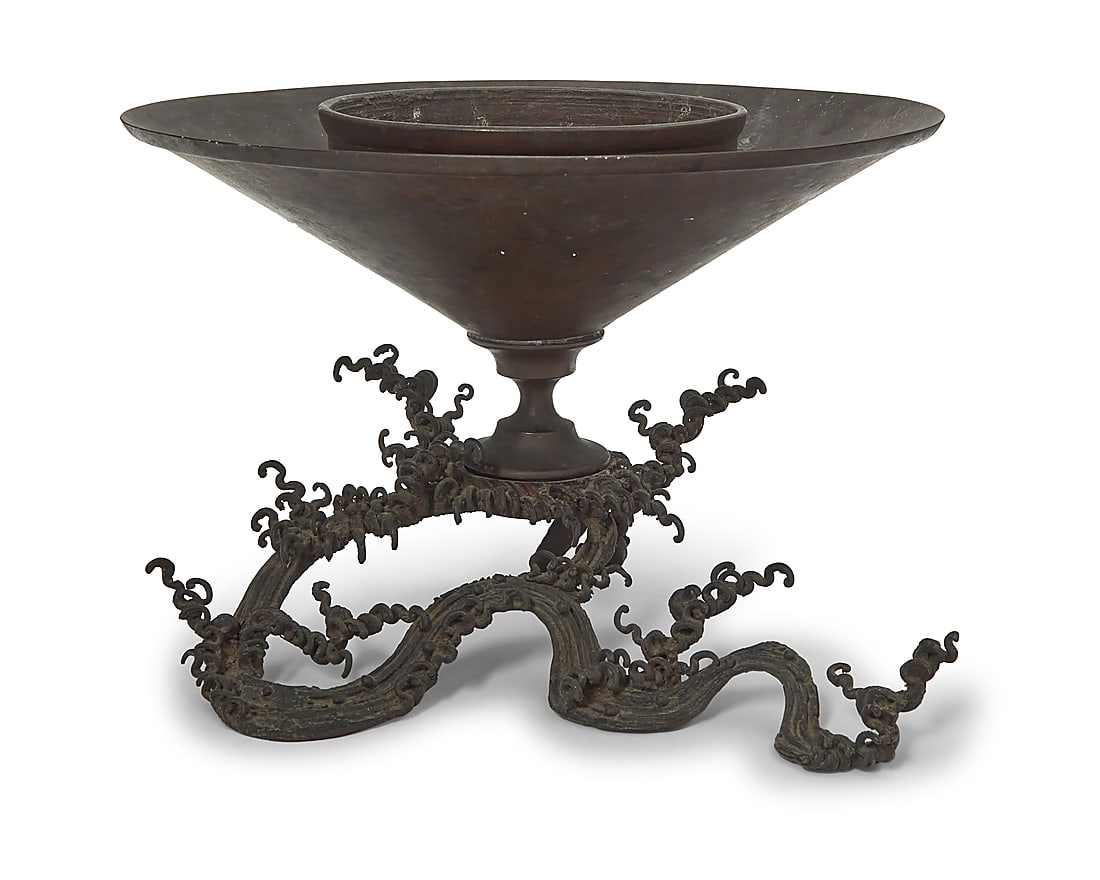 A Japanese metal usubata ikebana vase: A Japanese metal usubata ikebana vase 20th century The base in the form of roiling waves, issuing a cylindrical basin for floral display Height 7 1/4 in., width 12 1/2 in., depth 11 in.