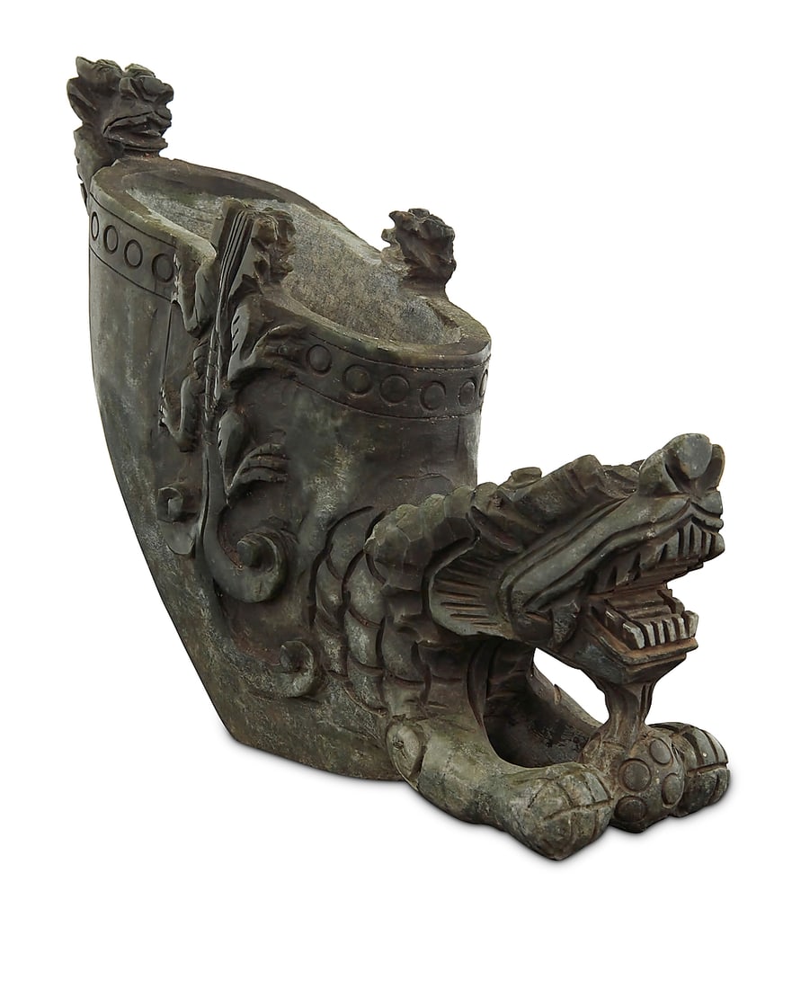 A Chinese carved stone brush pot: A Chinese carved stone brush pot 20th century Of dragon form, with smaller dragons in relief at the rim Height 8 1/4 in., width 10 3/8 in., depth 3 1/4 in.