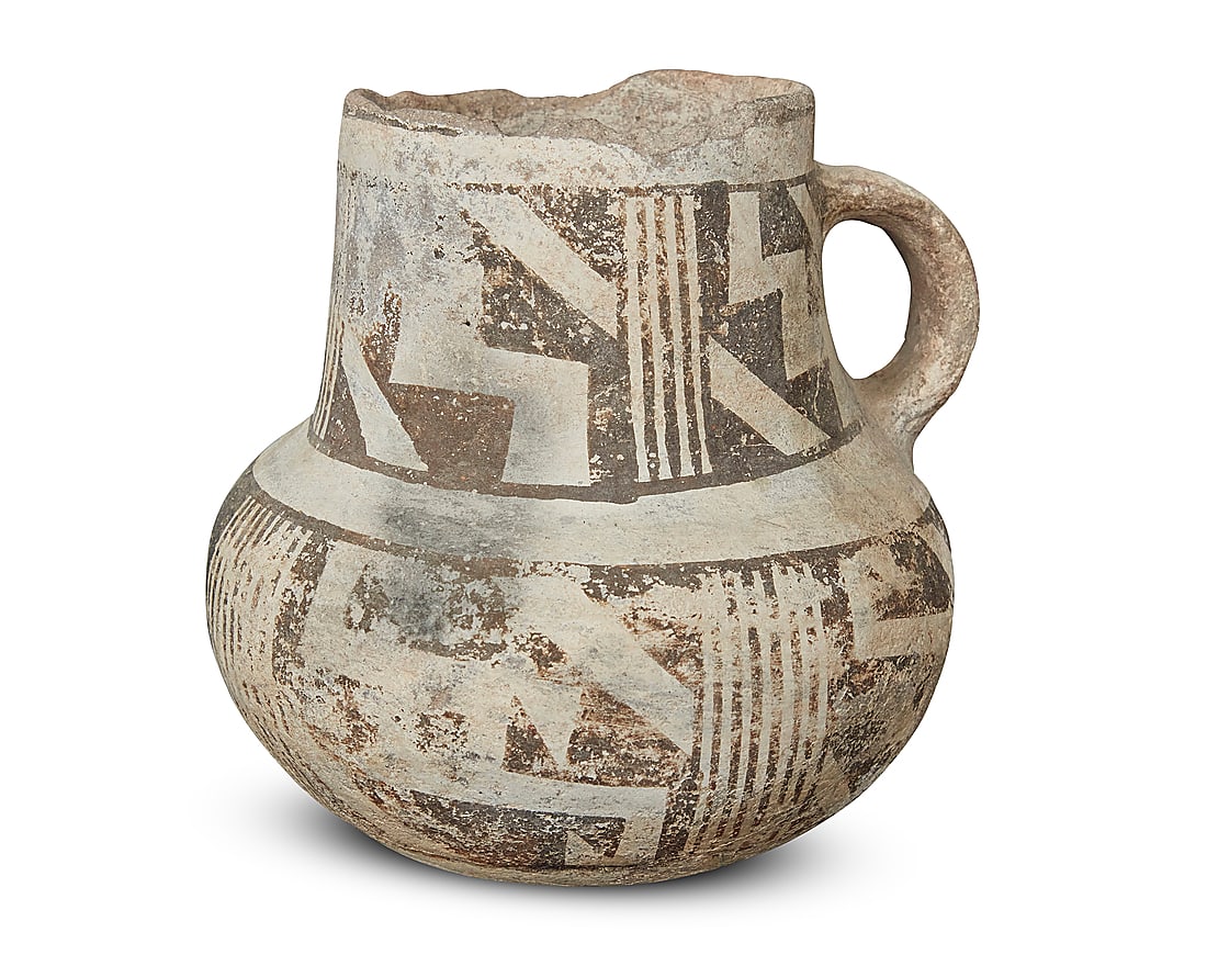 An Anasazi black on white pottery cup: An Anasazi black on white pottery cup 7th-14th century CE With lug handle, painted with black bands of geometric motifs on white slip ground Height 5 3/8 in., width 5 5/8 in., depth 5 3/8 in.