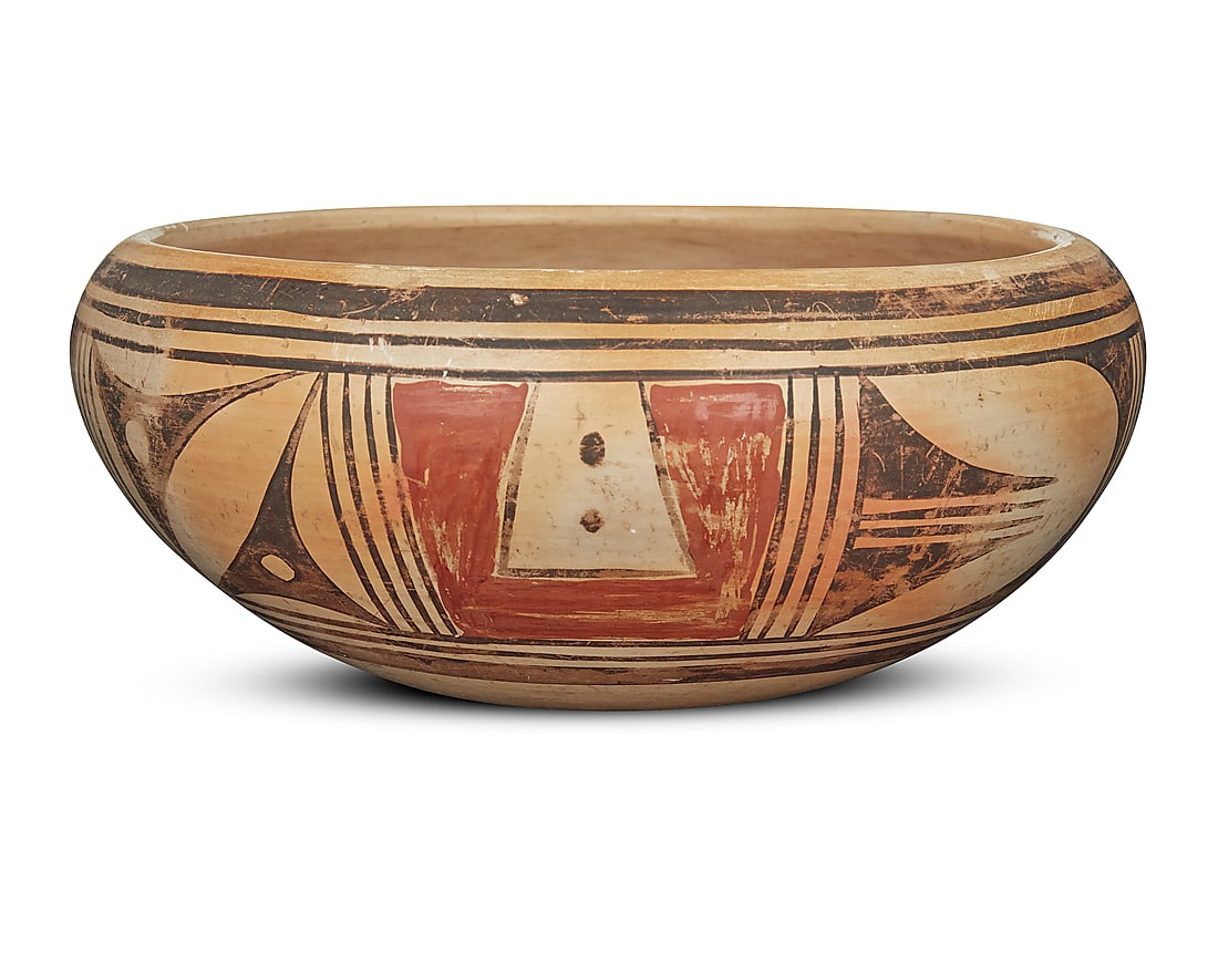 A Hopi polychrome yellowware pottery low bowl: A Hopi polychrome yellowware pottery low bowl Mid-20th century The exterior with red and black band of geometric motifs on cream slip ground Unmarked Height 4 in., diameter 9 3/4 in.