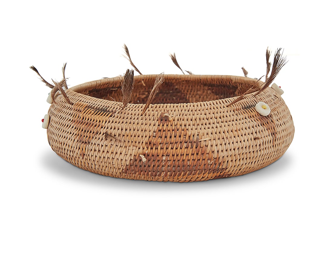 A Pomo beaded gift basket: A Pomo beaded gift basket Early/mid-20th century; Northern California A diminutive coiled basketry bowl with alternating triangle motifs, adorned with shell disc button beads and quail topknot