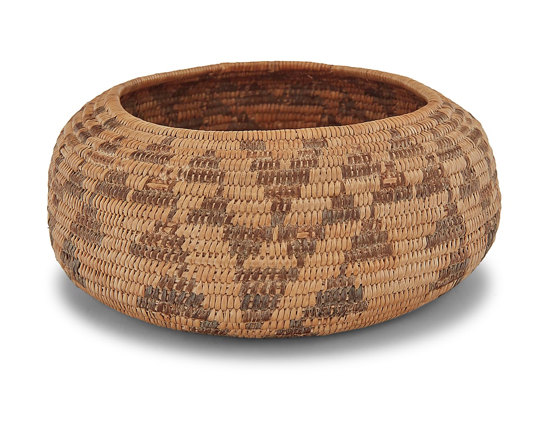A Pomo basketry bowl: A Pomo basketry bowl Mid-20th century; Northern California The small coiled low bowl with five columns of stacked zigzag triangle motifs Height 2 1/2 in., diameter 5 3/4 in. (variable)