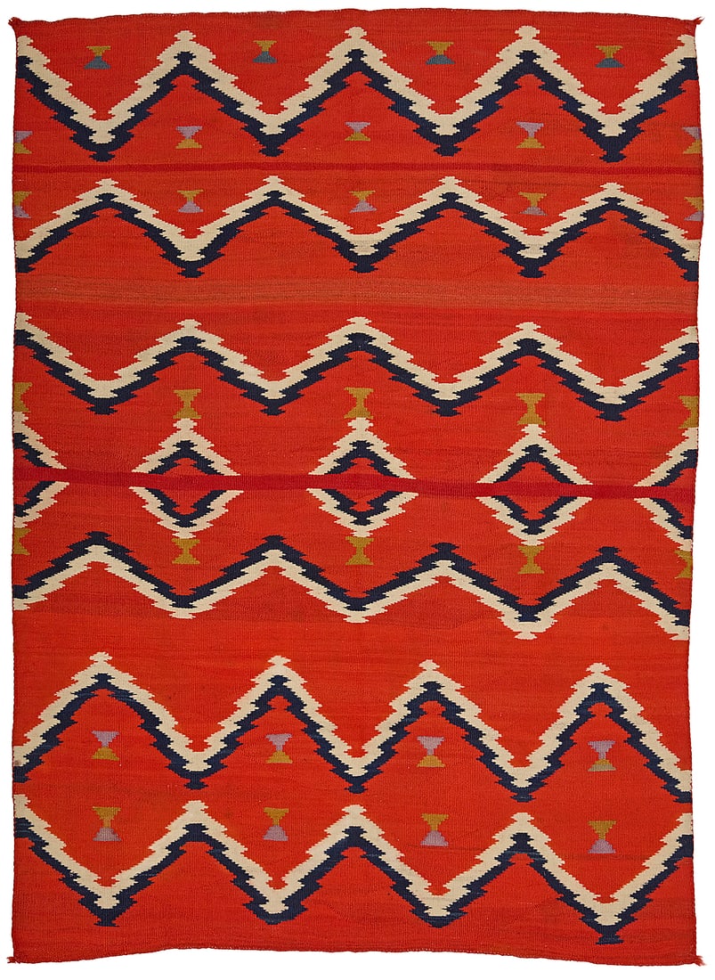 A Dine (Navajo) Late Classic sarape: A Dine (Navajo) Late Classic sarape Circa 1875-1885 Woven in red, cream, indigo, purple, and yellow wool with multiple bands of serrated barbed zigzags and floating serrated diamonds to center 4 ft.