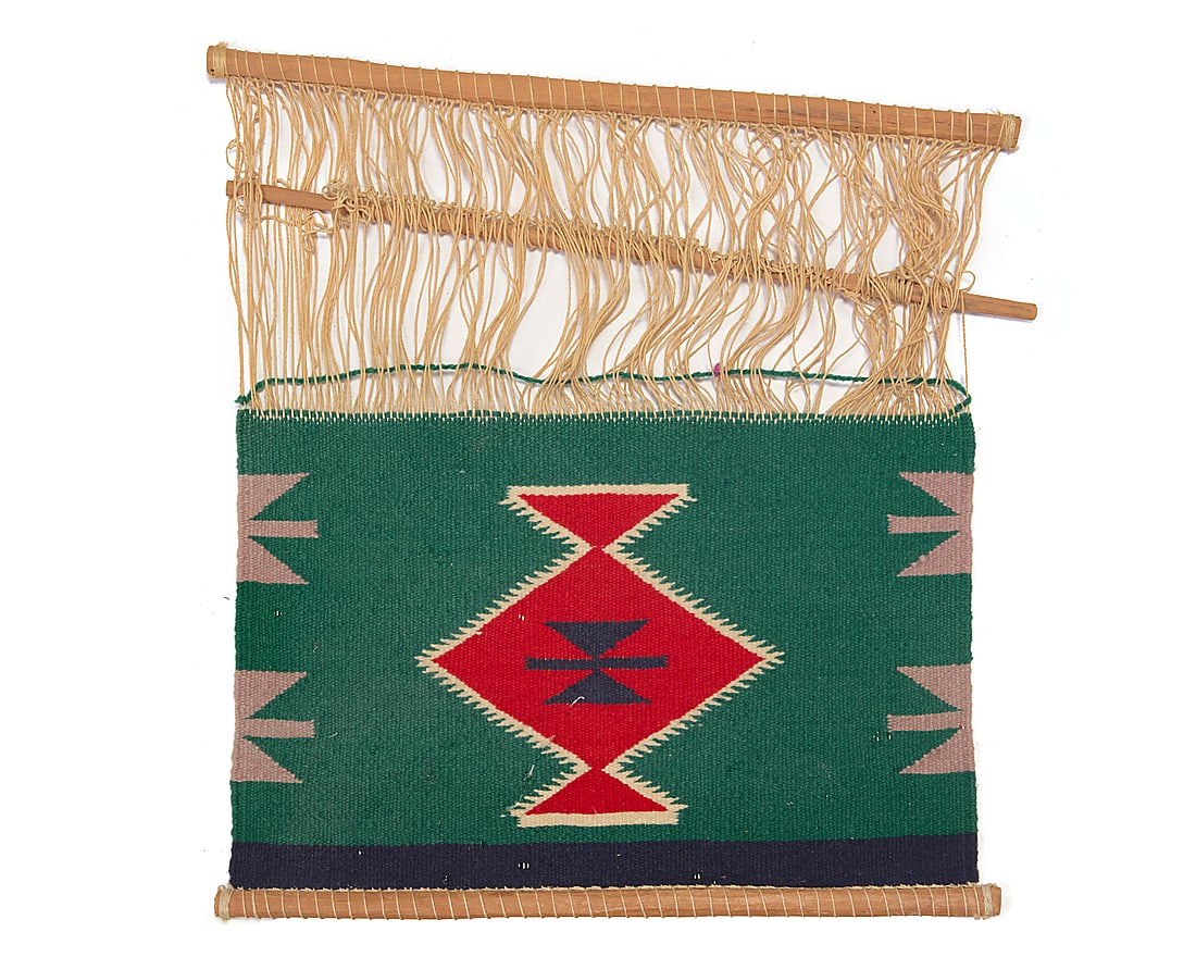 A Dine (Navajo) Germantown loomer: A Dine (Navajo) Germantown loomer Early 20th century Woven in green, red, blue, cream, and grey wool, with a central serrated diamond motif and triangular motifs to sides, with cotton warps and wooden