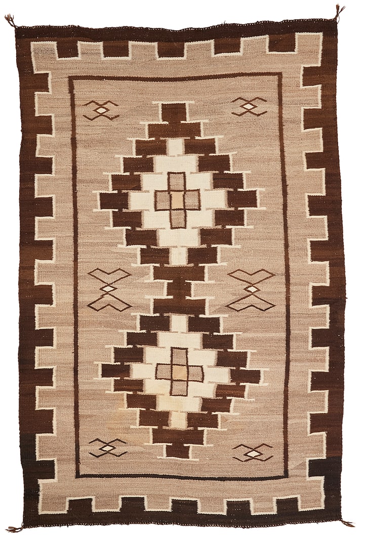 A Dine (Navajo) Two Grey Hills rug: A Dine (Navajo) Two Grey Hills rug Early 20th century With conjoined stepped diamonds and floating figural motifs within a denticulated border, woven in dark brown, cream, natural grey, and ochre wool