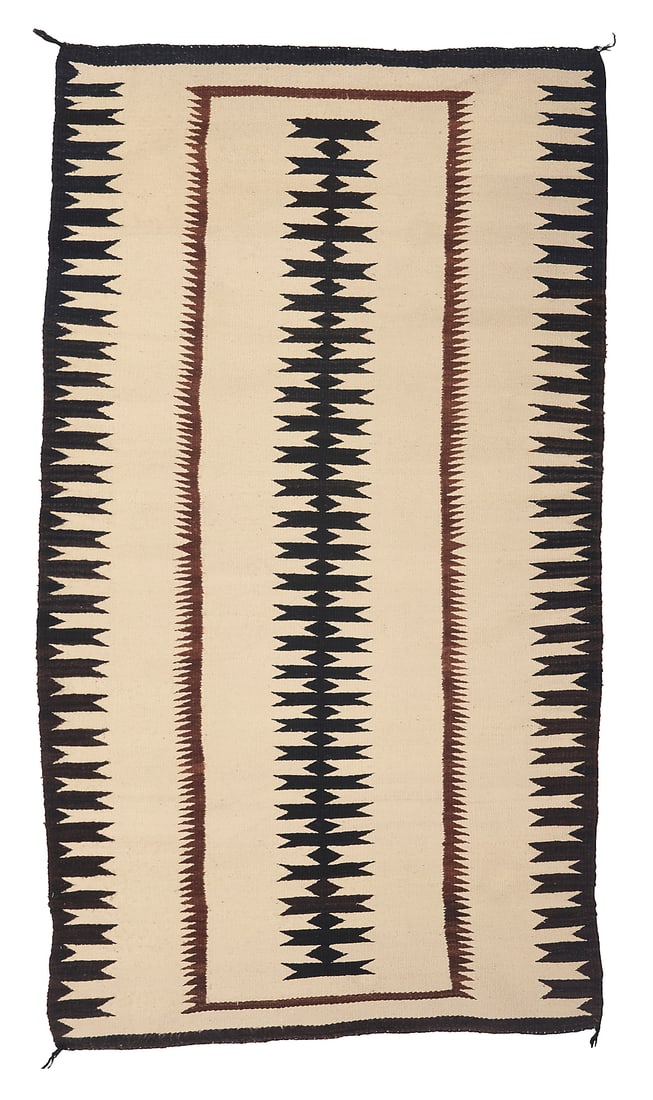 A Dine (Navajo) regional rug: A Dine (Navajo) regional rug Mid-20th century Woven in cream, brown, and black wool with a central narrow serrated column and similar complex serrated border to the long sides 5 ft. 8 in. x 3 ft. 2 in