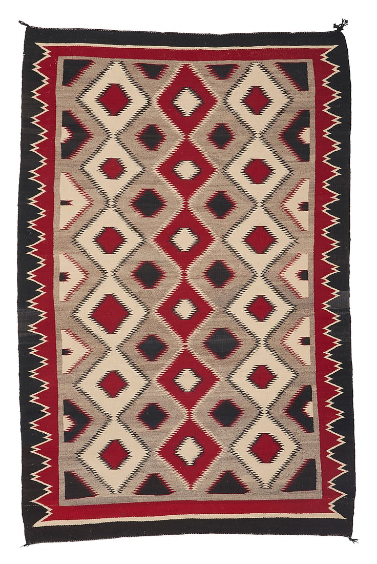 A Dine (Navajo) regional rug: A Dine (Navajo) regional rug Second half 20th century Woven in cream, red, grey, and black wool featuring multiple columns of alternating colored concentric serrated diamonds and with a complex sawtoo