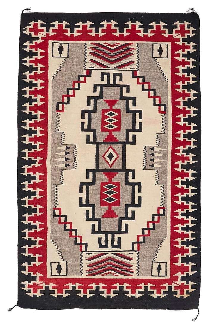 A Dine (Navajo) regional rug: A Dine (Navajo) regional rug Second half 20th century Woven in red, black, cream, and grey wool, with a central conjoined hooked stepped diamond, with feather elements and serrated elements to the end