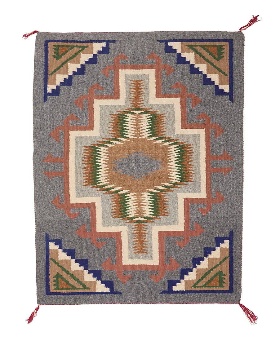 A Dine (Navajo) regional rug: A Dine (Navajo) regional rug Late 20th century Woven in grey, green, blue, tan, and salmon pink wool with central multicolored sawtooth and stepped hooked diamonds, with stepped motifs to each corner 