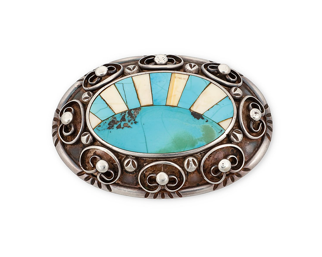 A Southwest sterling silver belt buckle: A Southwest sterling silver belt buckle Mid/late 20th century In a Zuni style, a chunky buckle featuring a central turquoise and bone inlay sunburst motif edged with applied curvilinear silver wire an