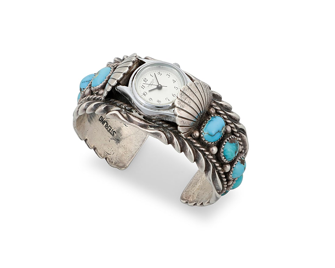Orville Tsinnie (1943-2017, Dine [Navajo]), A silver and turquoise watch cuff: Orville Tsinnie (1943-2017, Dine [Navajo]) A chunky sterling silver watch cuff with five graduated set turquoise cabochons to each shoulder and heavy stamping to edges, with attached watch face