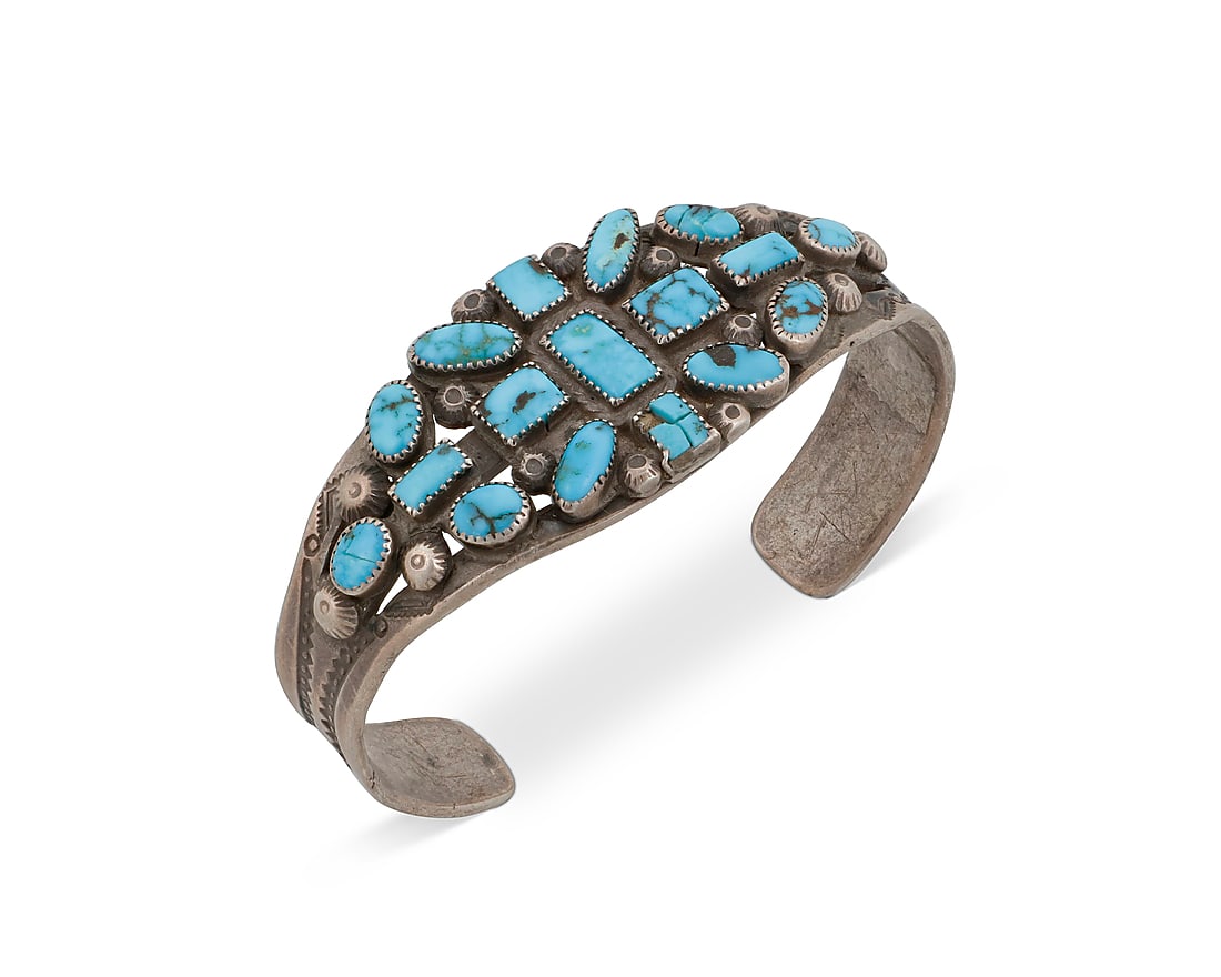 A Dine (Navajo) or Zuni sterling silver and turquoise cuff bracelet: A Dine (Navajo) or Zuni sterling silver and turquoise cuff bracelet Mid-20th century A three-wire pierced cuff with cluster-set oval and rectangular turquoise, stamped silver button accents and