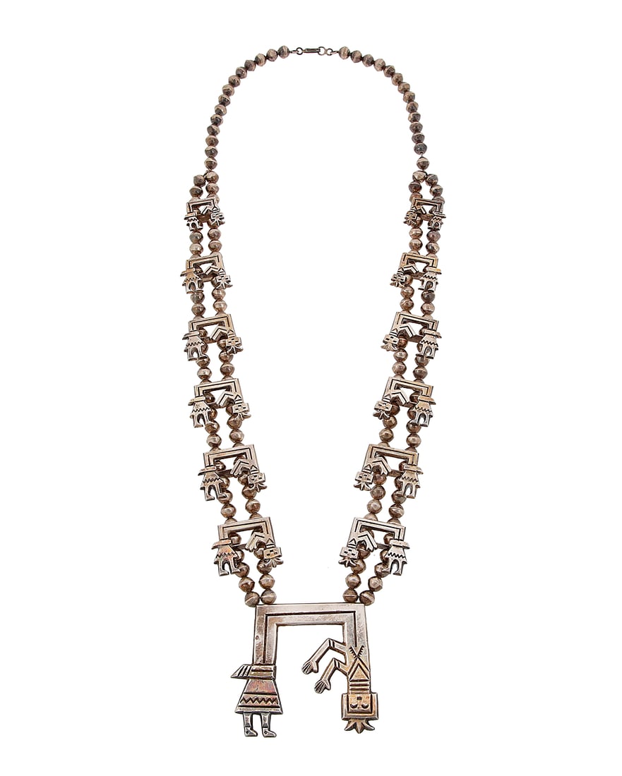 A sandcast silver Rainbow Guardian Yei necklace: A sandcast silver Rainbow Guardian Yei necklace Attributed to Francis Jones (b. 1943, Dine [Navajo]) A chunky double strand necklace with twelve graduated cast silver Yei figural 'blossoms', suspendin