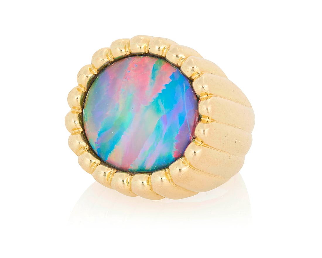 An 18K Gold and Black Opal Ring Of a high polish fluted design centering an oval black opal: An 18K Gold and Black Opal Ring Of a high polish fluted design centering an oval black opal cabochon measuring approximately 18.22 x 14.58 x 3.05 mm Size: 5 1/2 15.8 grams gross