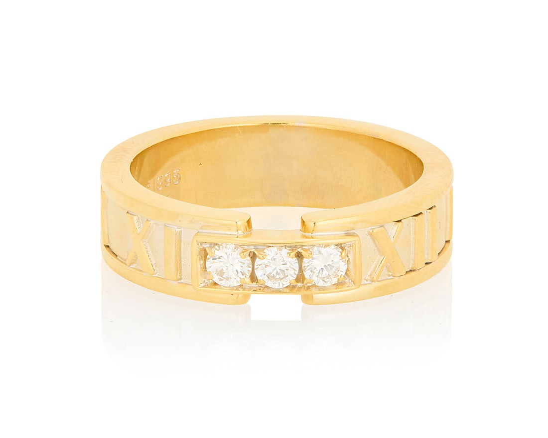 Tiffany & Co.: An 18K Gold and Diamond 'Atlas' Ring Featuring three round diamonds weighing: Tiffany & Co.: An 18K Gold and Diamond 'Atlas' Ring Featuring three round diamonds weighing approximately 0.15 carat, accented by high polish Roman numerals, signed Tiffany & Co. Size: 6 3/4 7.6 grams