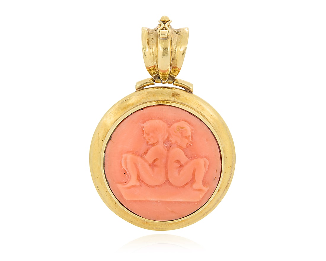 An 18K Gold and Coral Zodiac Pendant Centering a carved coral cabochon featuring the Gemini twins,: An 18K Gold and Coral Zodiac Pendant Centering a carved coral cabochon featuring the Gemini twins, set in a high polish gold frame, with French import marks Measures: 2 x 1 1/4 in. 18.6 grams gross