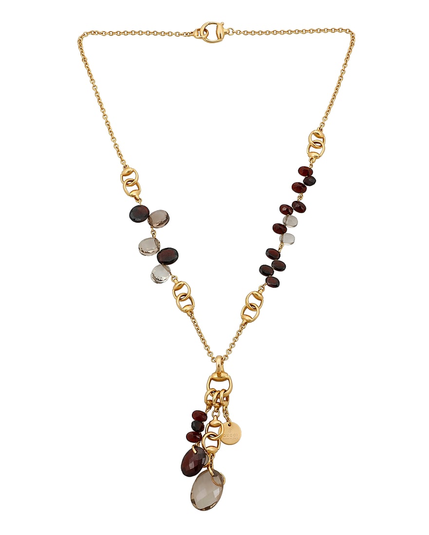 Gucci: An 18K Gold, Smoky Quartz and Garnet Necklace Featuring stirrup style gold links accented: Gucci: An 18K Gold, Smoky Quartz and Garnet Necklace Featuring stirrup style gold links accented by oval faceted garnet and smoky quartz, signed Gucci, with Italian assay marks Chain: 20 in., Tassel: 
