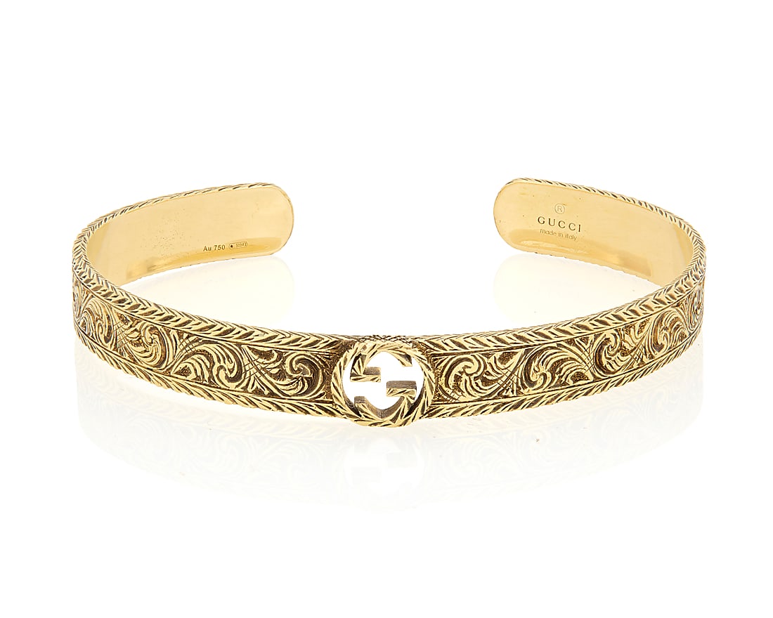 Gucci: An 18K Gold Bangle Featuring a scrolling engraved design centering an interlocking 'G', (1 of 4)