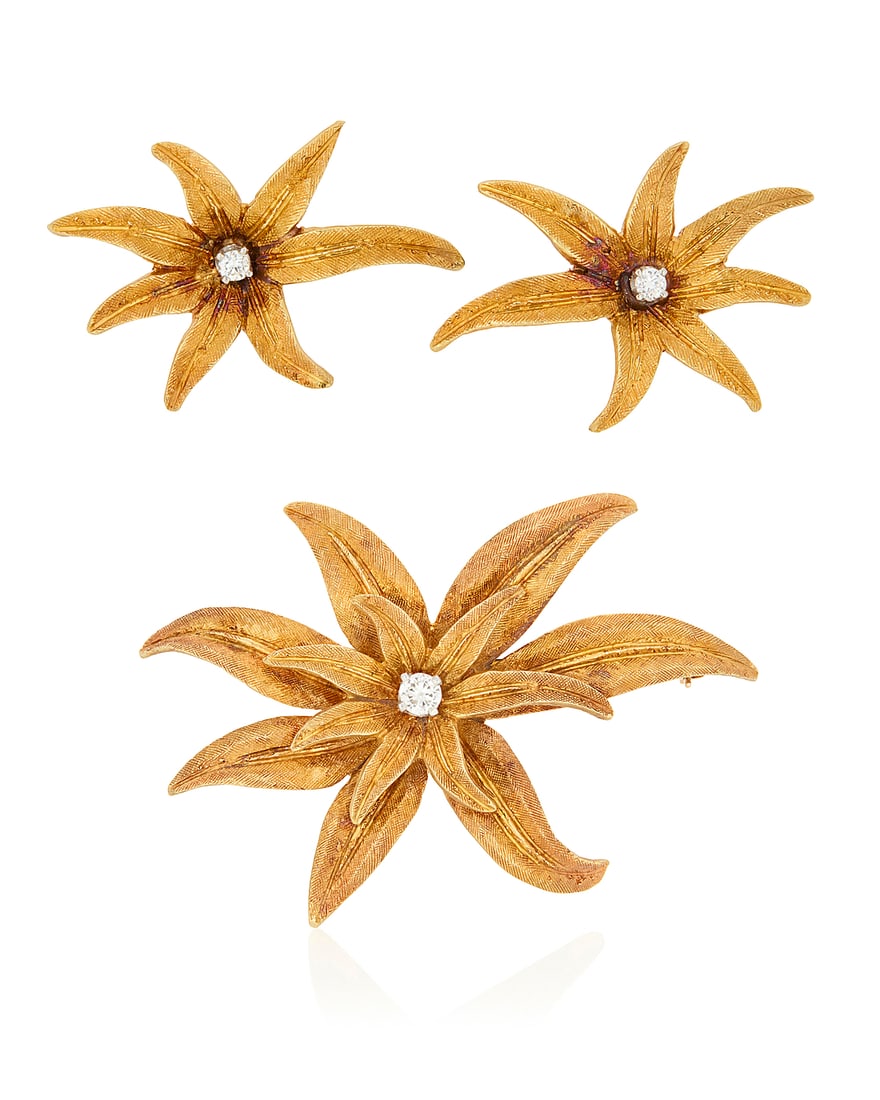 An 18K Gold and Diamond Brooch and Earring Set Of a flower motif, centering round diamonds 3: An 18K Gold and Diamond Brooch and Earring Set Of a flower motif, centering round diamonds 3 pieces Brooch: 2 1/2 x 1 1/2 in., Earrings: 1 1/4 x 7/8 in. 21.7 grams gross